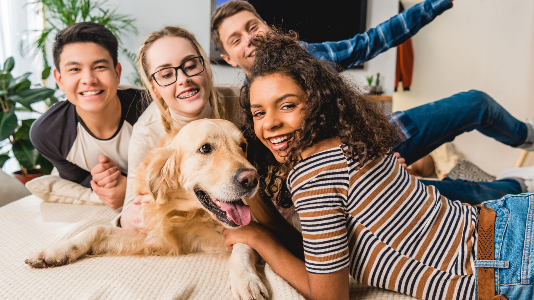 happy multiethnic teenagers palming dog and looking at camera